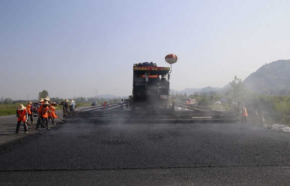 2019年8月，宜春經(jīng)開(kāi)區(qū)S311路面攤鋪現(xiàn)場(chǎng)，工友們輔助路面兩側(cè)的分料、補(bǔ)窩等作業(yè)